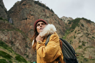 Young woman standing against mountain