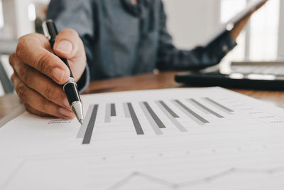 Midsection of businessman analyzing paperwork on desk in office