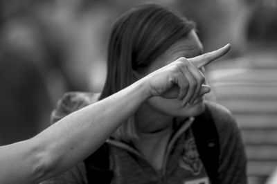 Cropped hand of woman pointing away outdoors