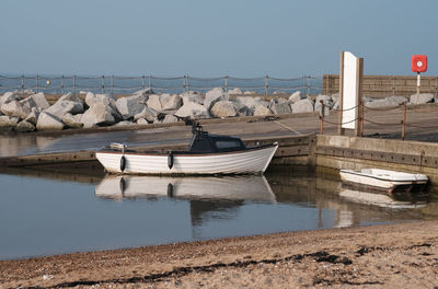 Boats moored at harbor against sky