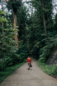 Rear view of woman walking on footpath amidst trees