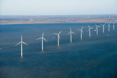 Wind turbines in sea against sky