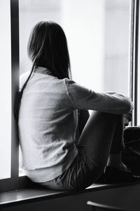 Rear view of girl sitting at home