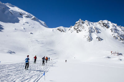 People skiing on snowcapped mountain against sky