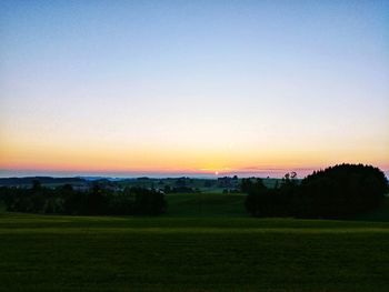 Scenic view of field against clear sky during sunset