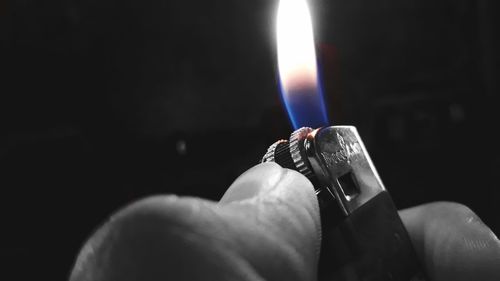 Close-up of hand holding candle against black background