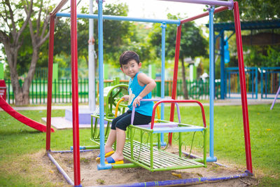 Side view of boy sitting on slide at playground