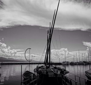 Sailboats moored at harbor against sky