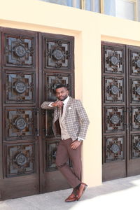 Full length of young man standing against door