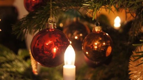 Close-up of illuminated christmas lights by balls on tree