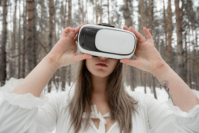 Woman wearing virtual reality simulator against trees outdoors