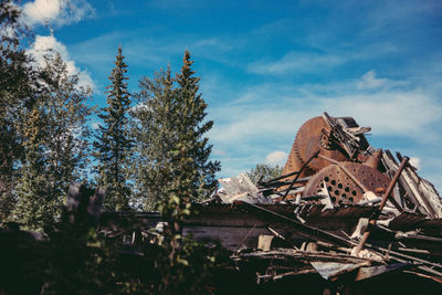 Low angle view of shipwreck by trees against sky