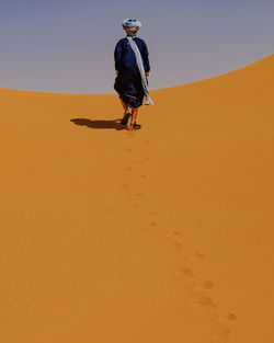 Man walking on sand dune in desert