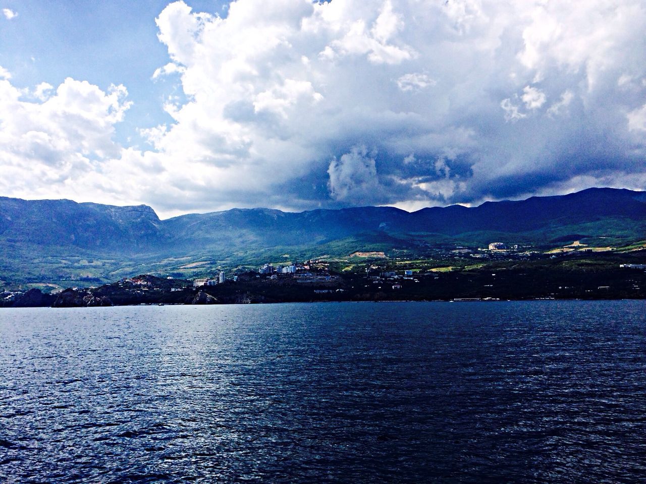 mountain, sky, mountain range, water, waterfront, building exterior, cloud - sky, architecture, scenics, built structure, city, cityscape, cloud, sea, beauty in nature, tranquil scene, river, tranquility, nature, cloudy