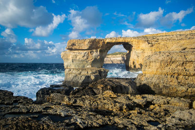 Rock formations on sea shore against sky