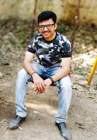 Portrait of smiling young man sitting on swing