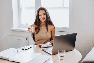 Portrait of young woman using phone on table