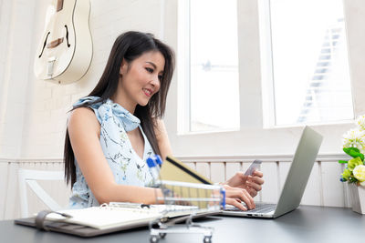 Young woman using phone while sitting on table