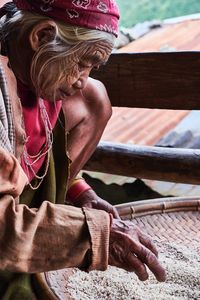 Woman cleaning grain while sitting on bench