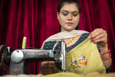 Portrait of young woman using sewing machine