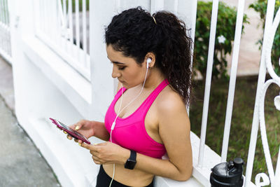 Portrait curly young woman, wearing a smartphone and taking a break