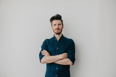 Handsome young man in a dark blue shirt by a light wall. place for text. high quality photo