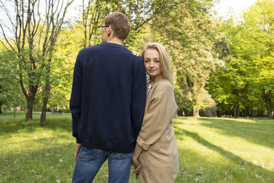 Young woman standing against trees