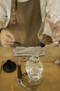 Midsection of lawyer holding wineglass on table