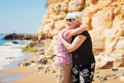 Two senior women are metting on a walk along a rocky beach