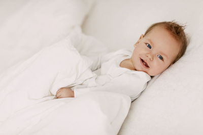 Portrait of cute baby lying on bed