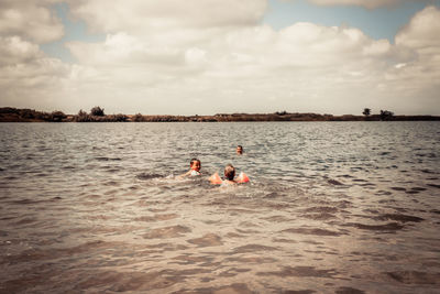 Men swimming in sea against sky