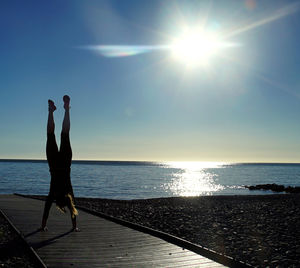 Silhouette woman by sea against sky during sunset