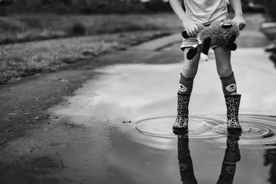 Low section of boy standing in puddle