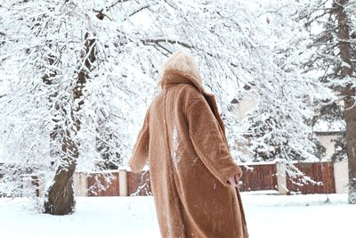 Rear view of woman standing against snow covered trees outdoors