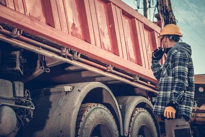 Side view of worker standing by truck at construction site