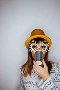 Portrait of woman holding cup against gray background