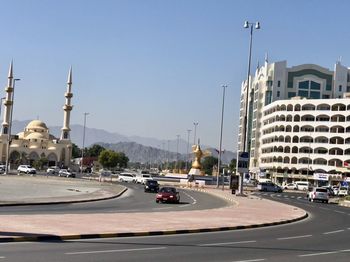 Cars on street by buildings against clear sky