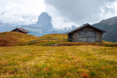 House on field by mountain against sky