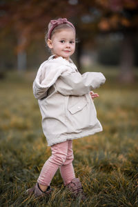 Portrait of cute girl standing on grassy field
