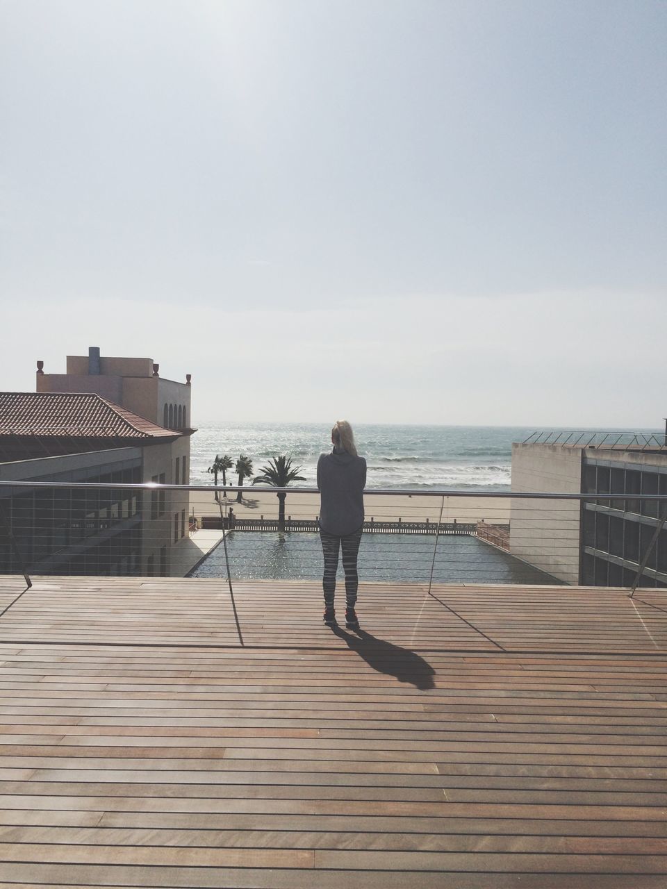 sea, horizon over water, water, rear view, sky, full length, pier, lifestyles, men, built structure, beach, leisure activity, walking, tranquility, wood - material, railing, standing, person