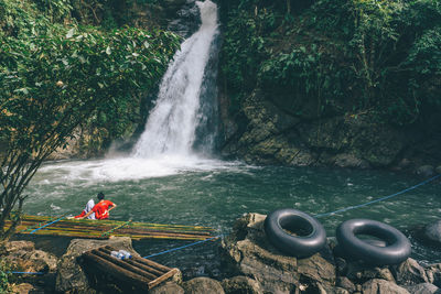 Man standing by waterfall against trees