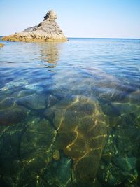 Rock formation in sea against clear sky