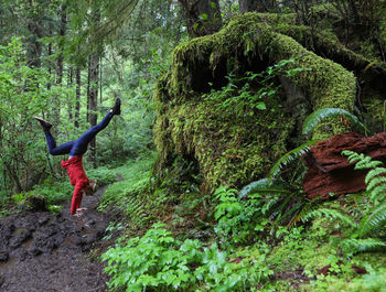 Woman doing handstand in forest