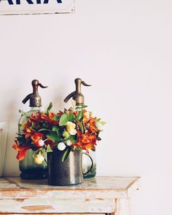 Flowers in vase on table against wall