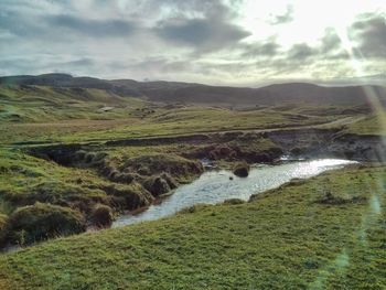 Scenic view of river against cloudy sky