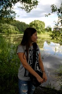 Young woman looking away while standing on lakeshore