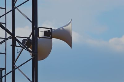 Low angle view of speakers on pole against sky