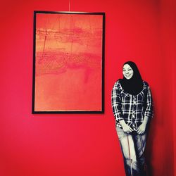 Portrait of woman standing against red wall