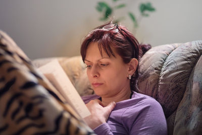 Girl looking away while relaxing on bed at home