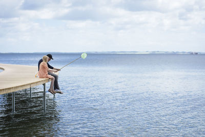 Man fishing in sea against sky